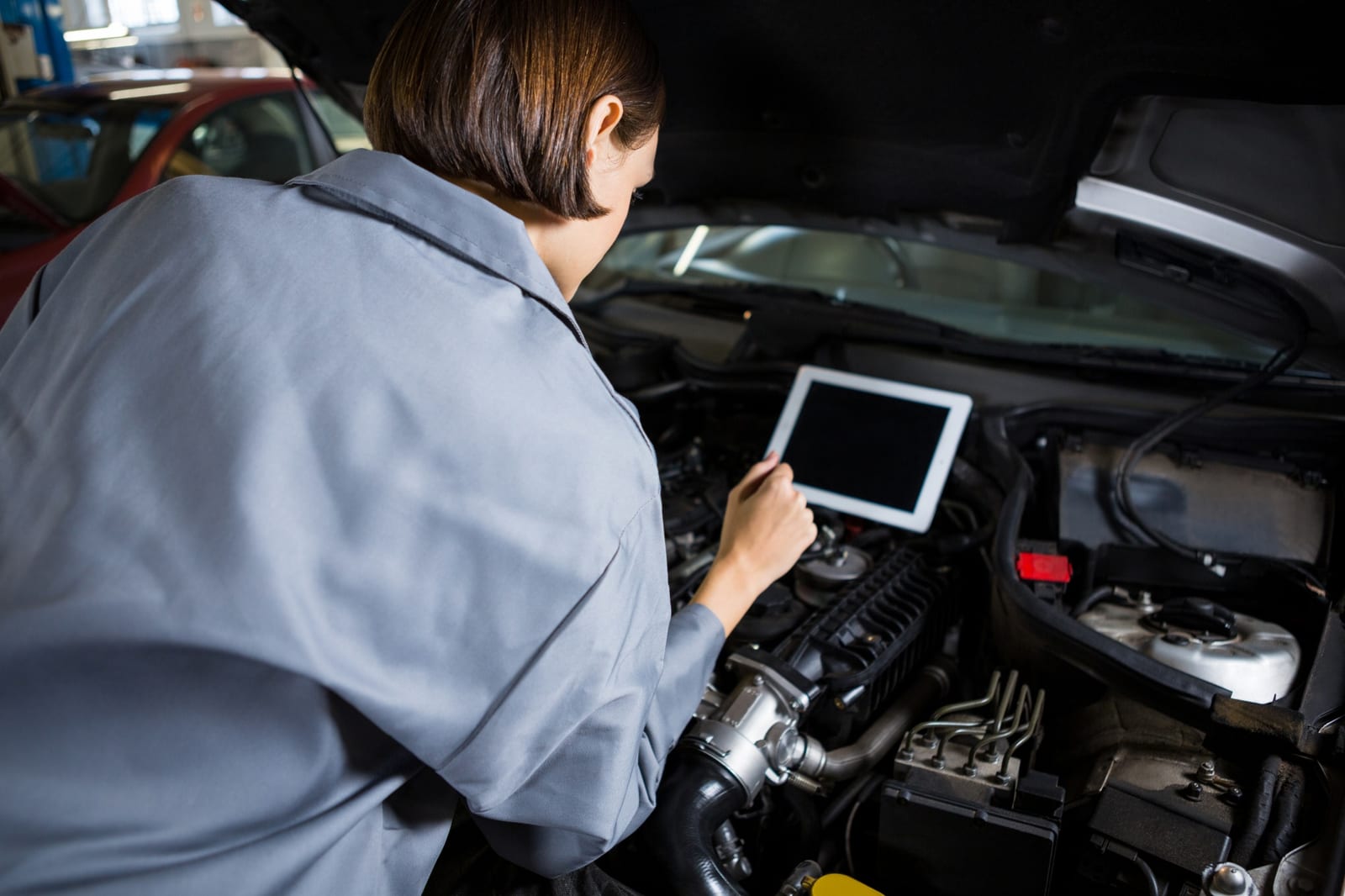 Técnica revisa dados de diagnóstico em um compartimento de motor aberto